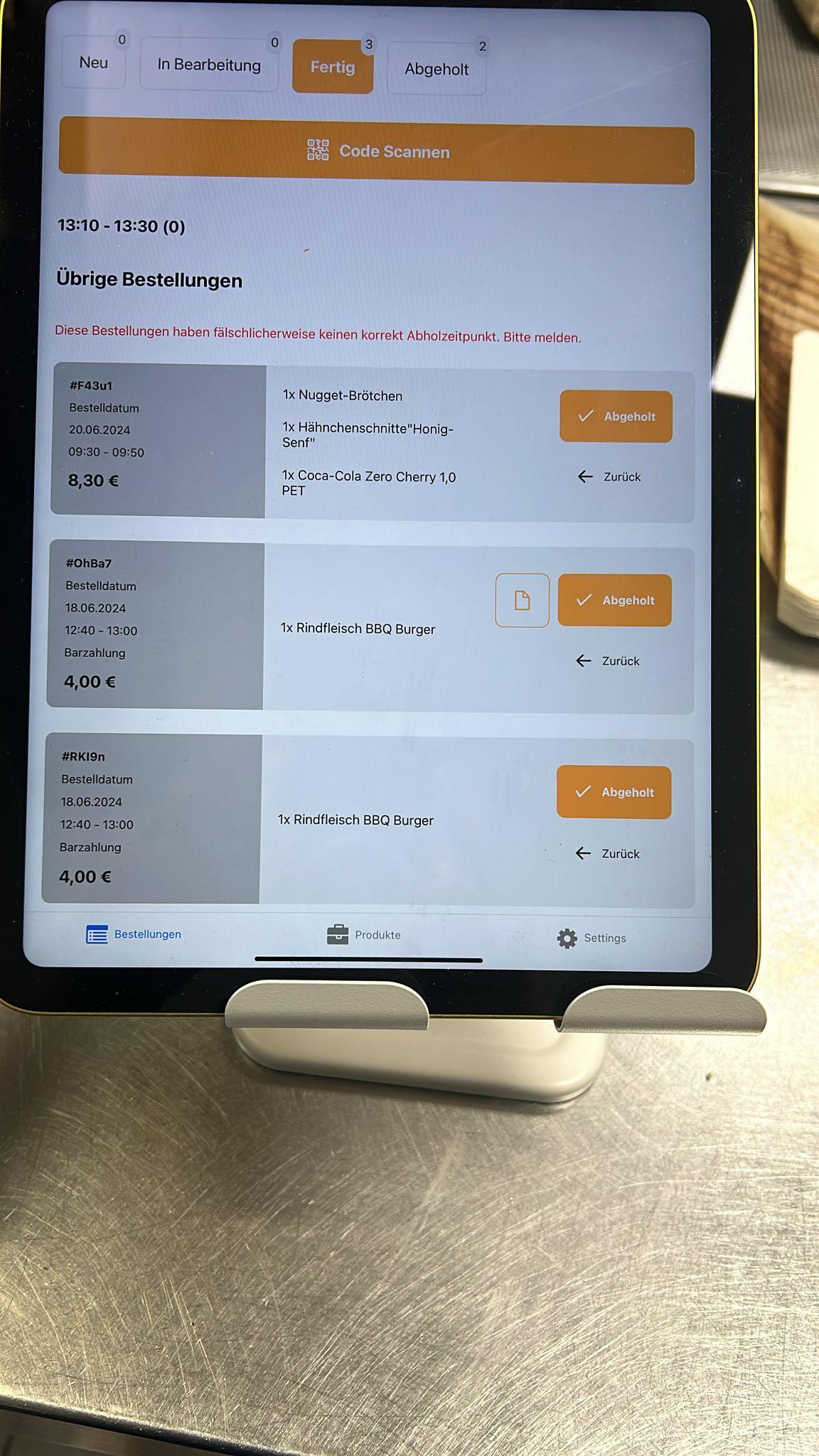 Tablet mit mehreren echten Kantinenbestellungen und einem Hinweis auf fehlerhafte Abholzeiten.